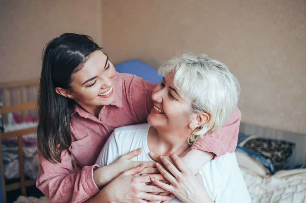 Beautiful mature blonde mom and her adult brunet daughter are hugging