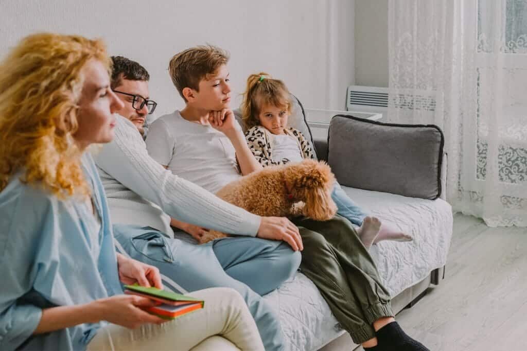 The family is sad home, in quarrel on the couch: dad, mom, teen son, preschool daughter, poodle dog