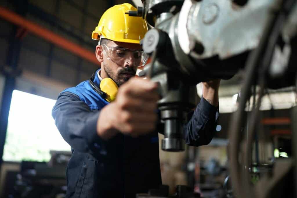 Worker at machine in factory, Metal industry worker at factory.